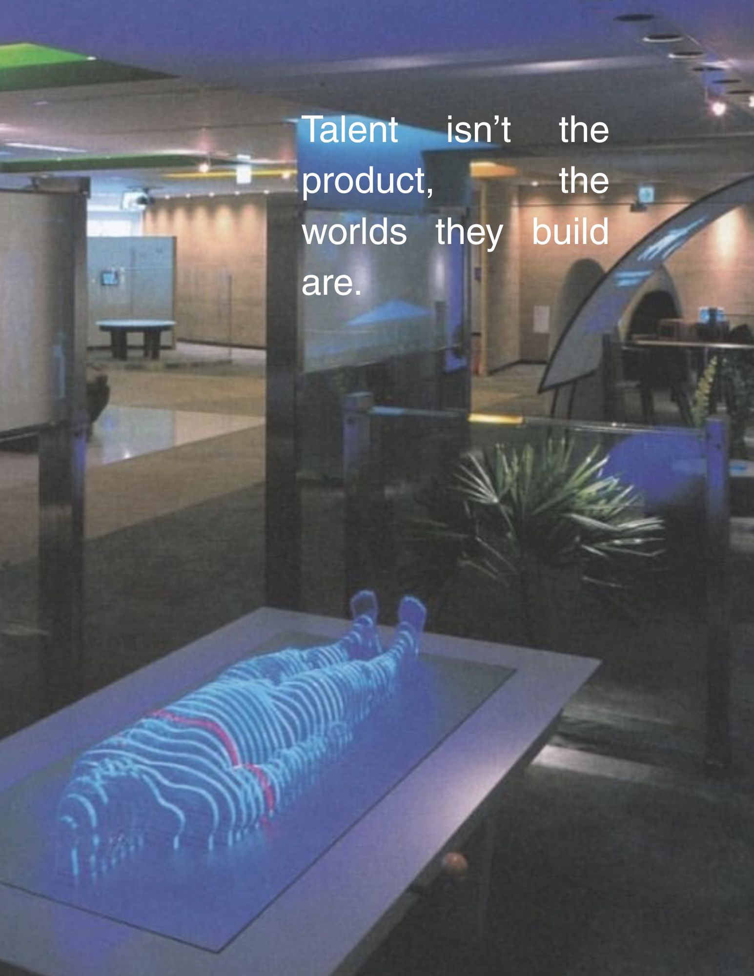 A holographic scan of a reclining figure on a table, with the text: Talent isn't the product, the worlds they build are.